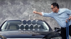 Akio Toyoda builds a tower of champagne glasses on the hood of a Lexus LS 500