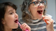 Woman and Child Brushing Their Teeth Together