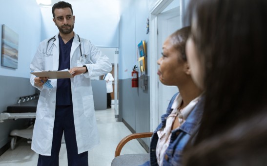 Man in White Medical Scrub Suit Standing Beside Girl in Blue Denim Jacket