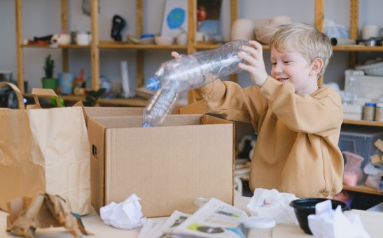 Smiling Boy Putting Plastic Bottles on a Box
